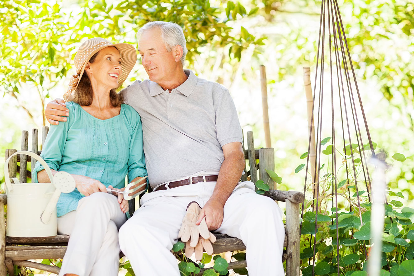 Photo of a retired couple sitting on a bench in the garden.